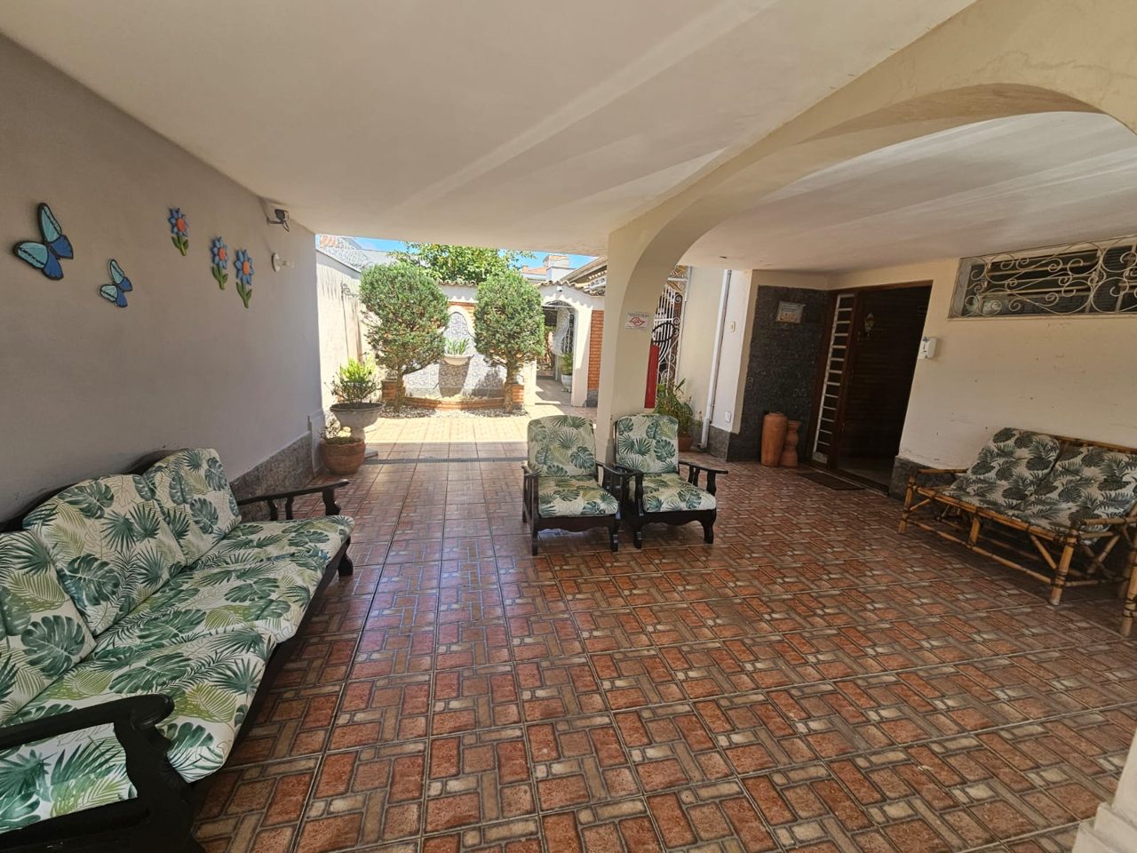 Área de convivência coberta com sofás e jardim ao fundo