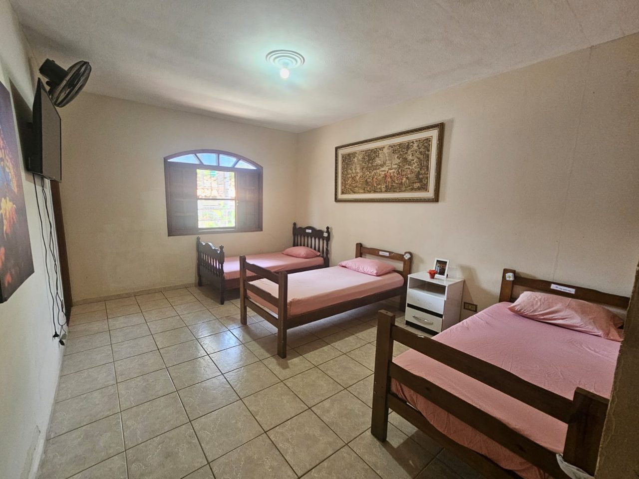 Quarto amplo com três camas e janela em arco
