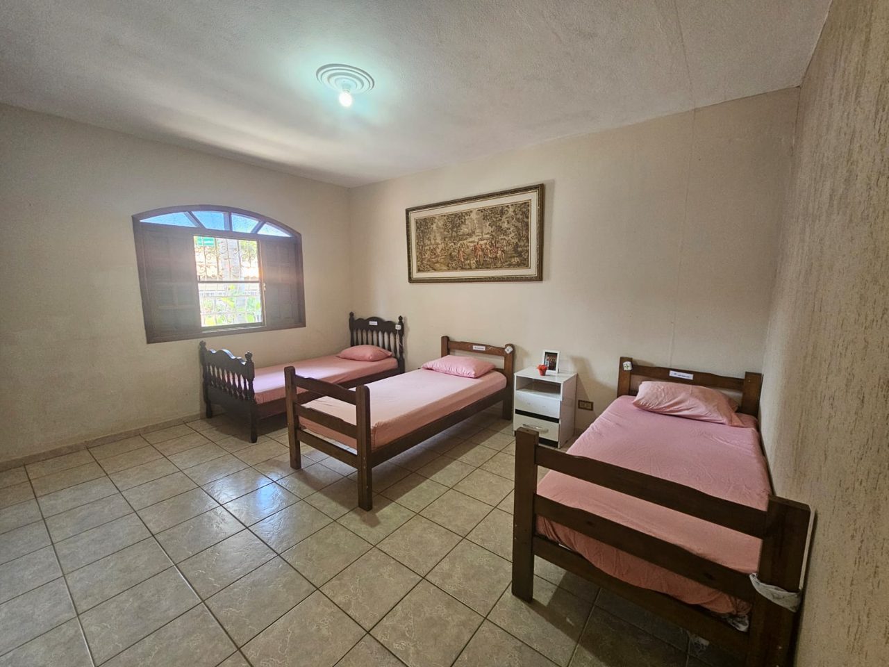 Quarto espaçoso com três camas e tapeçaria
